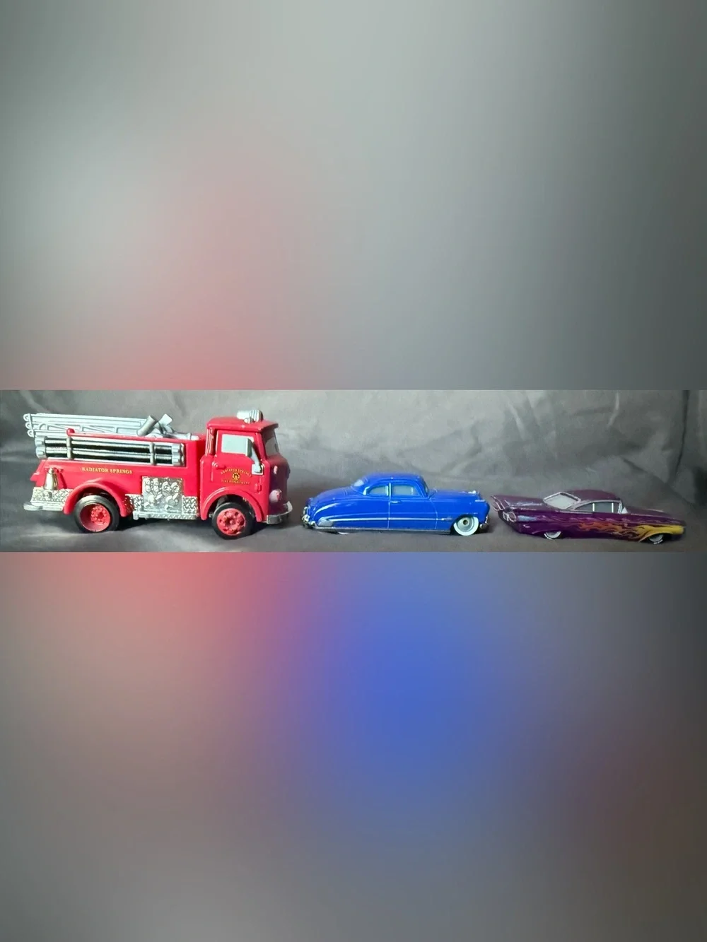 Disney Pixar Cars Diecast: Red Fire Truck, Doc Hudson, and Purple Ramon.